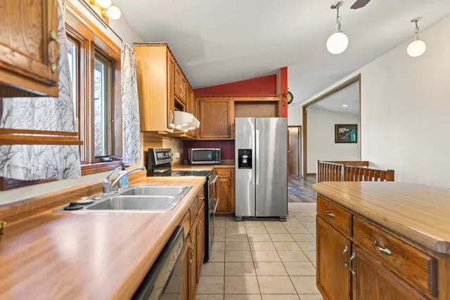 a kitchen with stainless steel appliances granite countertop a sink a stove and a refrigerator