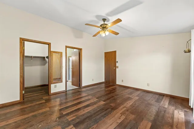 a view of an empty room with wooden floor and window