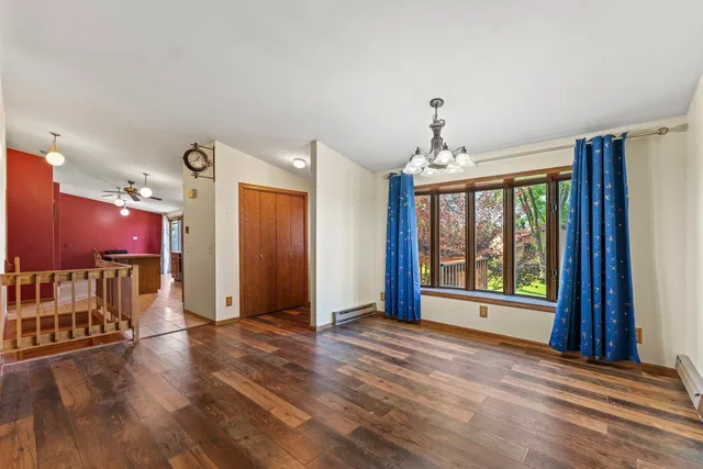 a view of an empty room with a window and wooden floor
