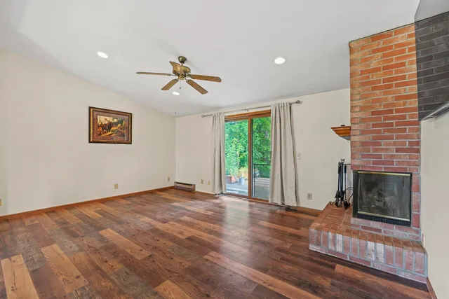 a view of empty room with wooden floor and fireplace