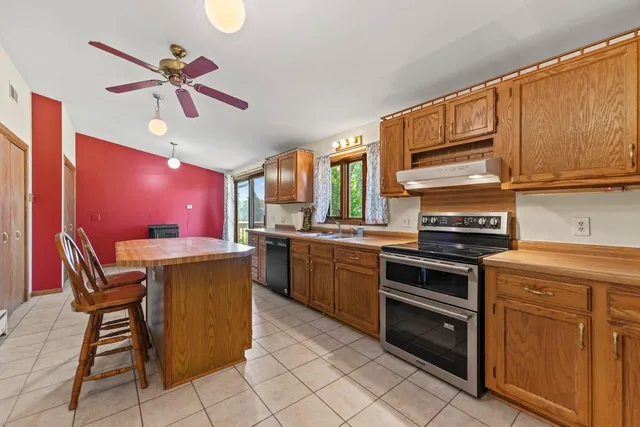 a kitchen with stainless steel appliances granite countertop a stove top oven a sink a dining table and chairs with wooden floor