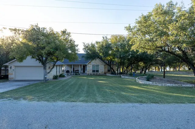 a view of a big house with a big yard and large trees