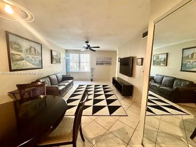 a living room with a black white checkered floor with a gaming machine and wooden floor