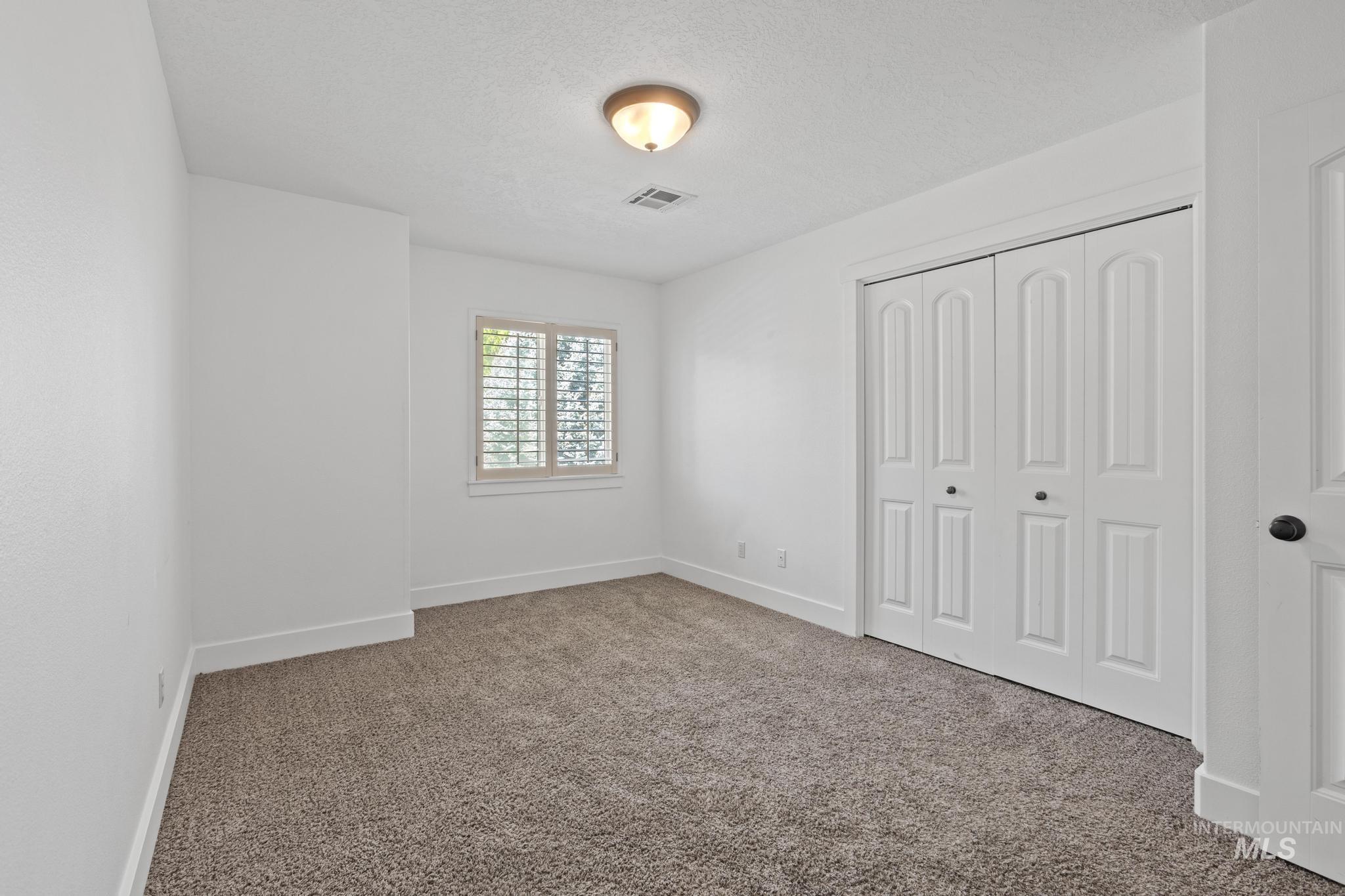 5271 West Morris Hill Road Boise, ID 83706 - Photo 22 of 31 Unfurnished bedroom featuring carpet flooring, a textured ceiling, and a closet