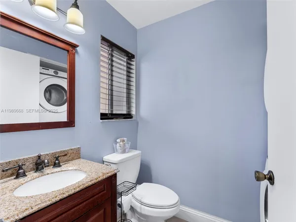 a bathroom with a granite countertop sink vanity mirror and toilet