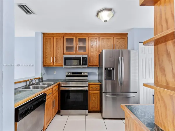 a kitchen with stainless steel appliances granite countertop a refrigerator stove top oven and sink