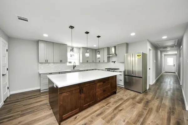 a large kitchen with stainless steel appliances granite countertop a sink a stove and a refrigerator