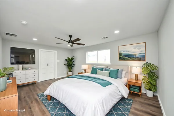 a spacious bedroom with a bed and a flat screen tv