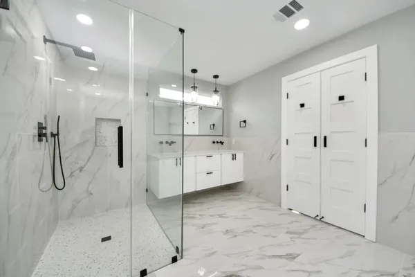a bathroom with a glass shower door a sink and a shower