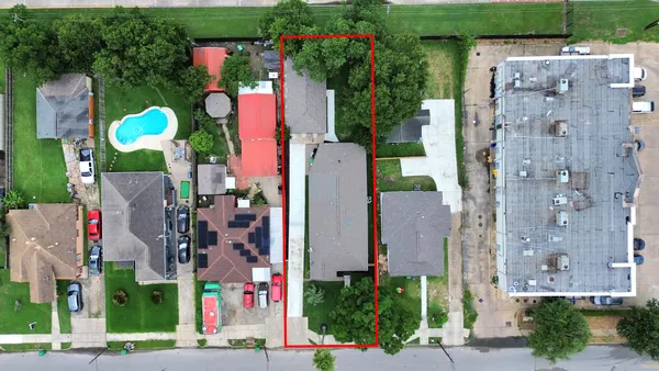 a aerial view of multi story residential apartment building with yard and retail shops