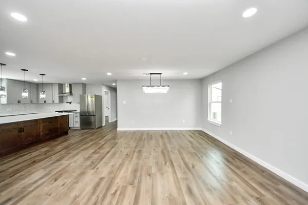 a large kitchen with kitchen island a sink dishwasher a stove and a refrigerator with wooden floor