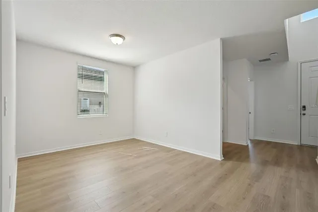 a view of an empty room with wooden floor and a window