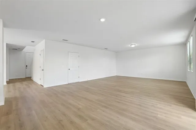 a view of an empty room with window and wooden floor