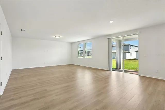 a view of an empty room with a window and wooden floor