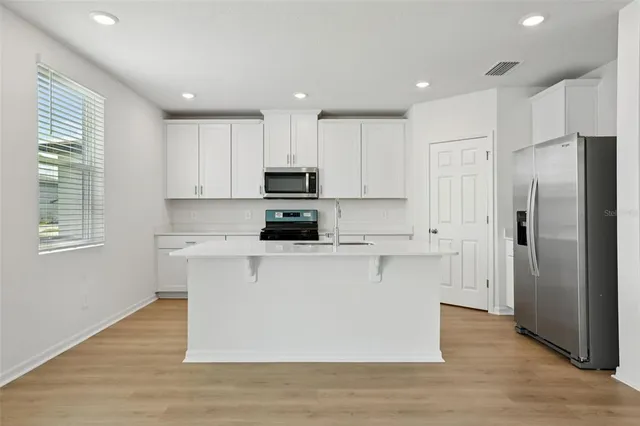 a kitchen with cabinets stainless steel appliances and wooden floor