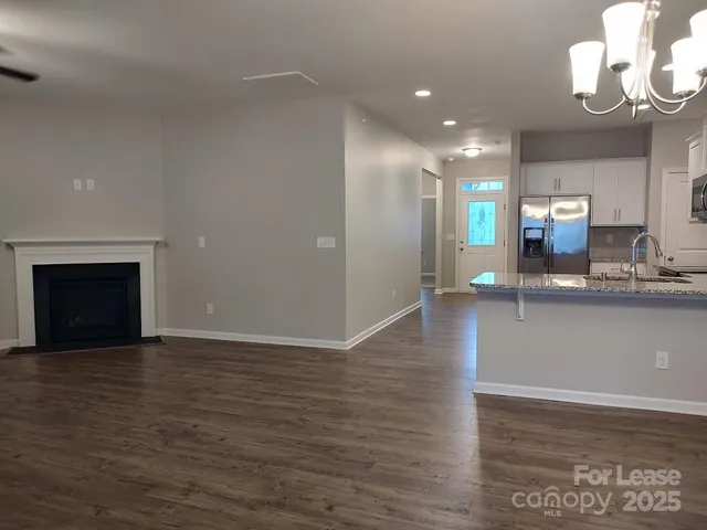 a view of a kitchen with granite countertop a stove top oven a sink and dishwasher with wooden floor