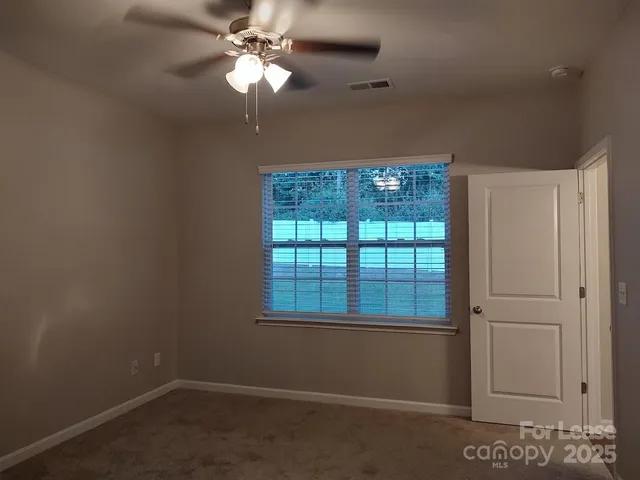 an empty room with a window and a fan