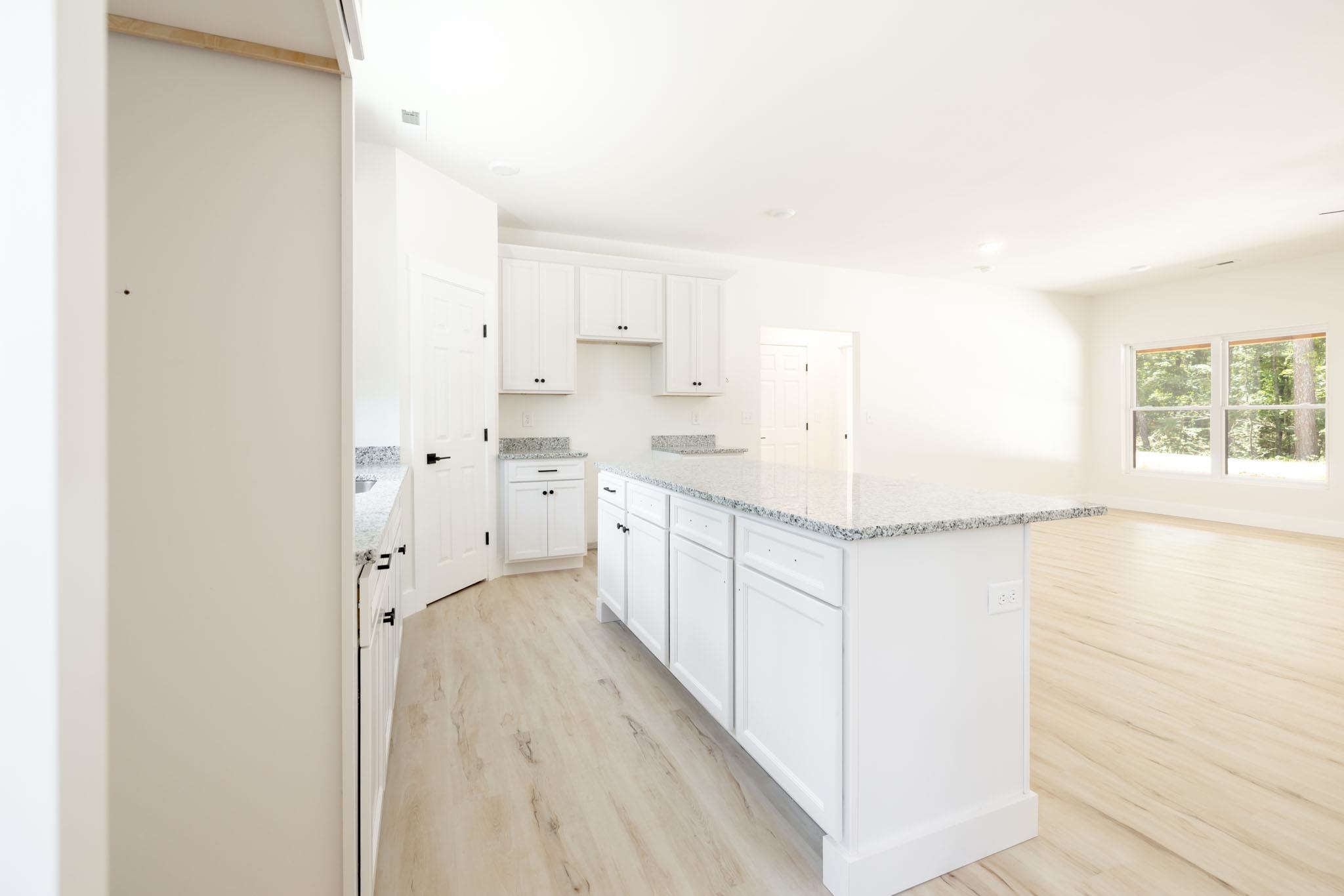 37 William Teague Lane Ramer, TN 38367 - Photo 18 of 39 Open-concept kitchen featuring white cabinetry, light-toned wood-finish flooring, and granite countertops