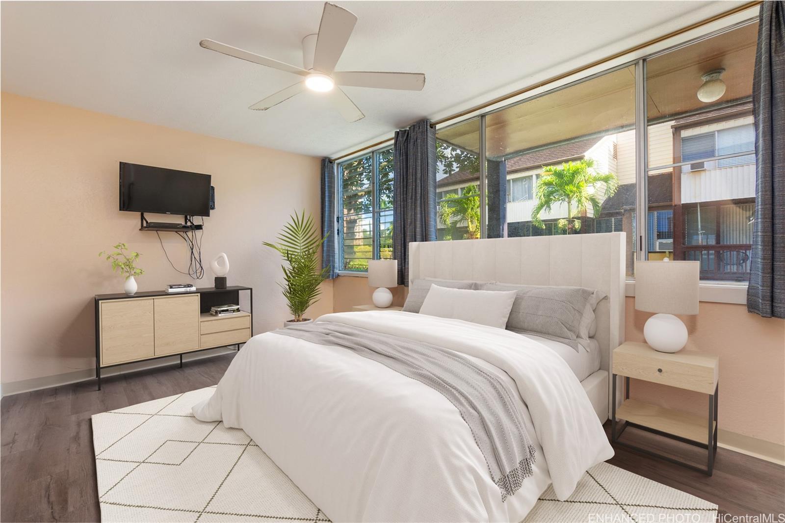 98-360 Koauka Loop, Unit 243 Aiea, HI 96701 - Photo 12 of 25 a bedroom with a bed a flat screen tv and a large window with the potted plants