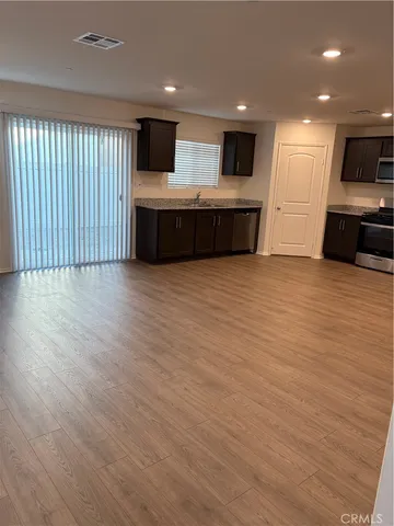 a view of kitchen and empty room with wooden floor