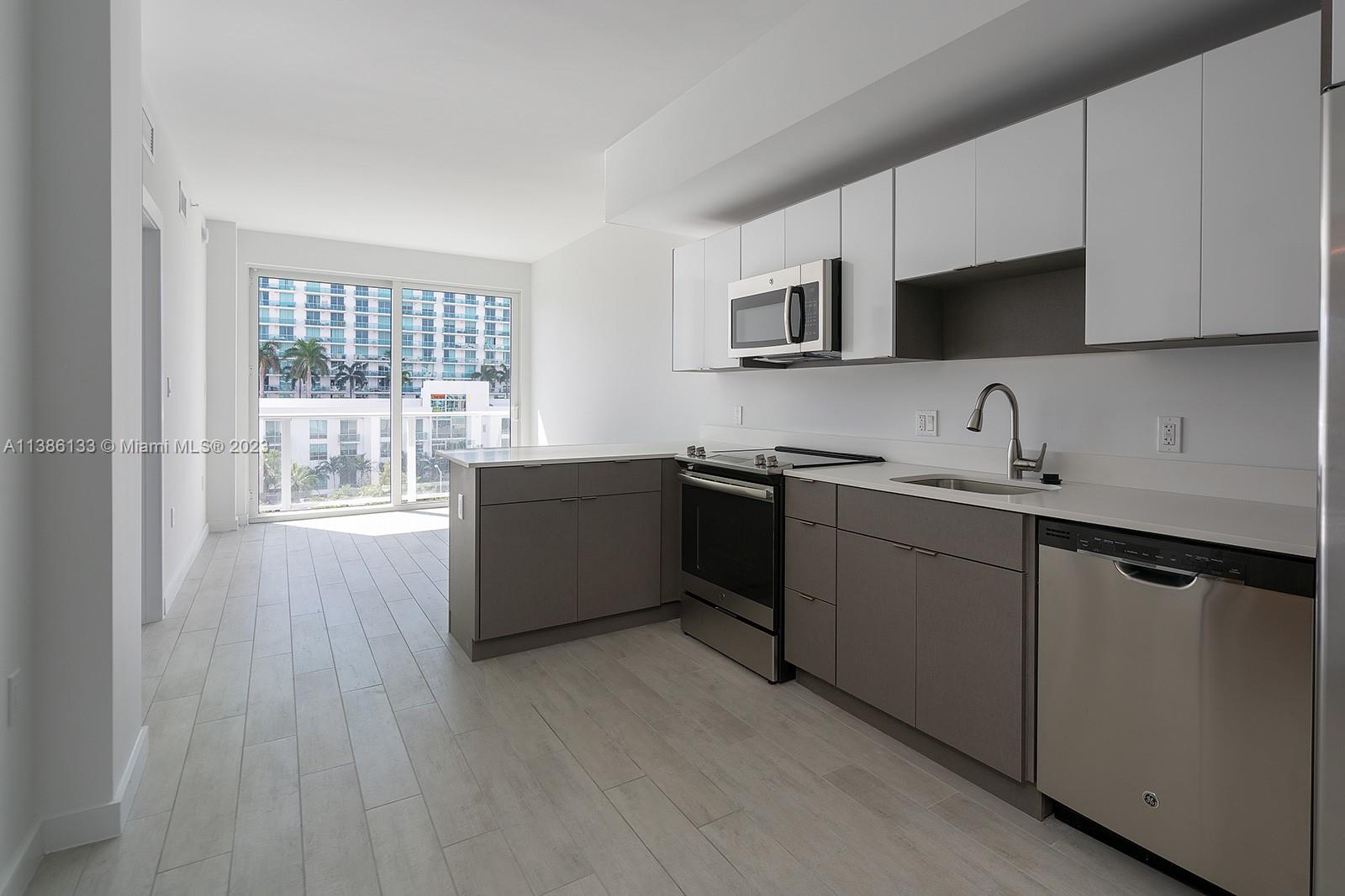 321 Northeast 26th Street, Unit 615 Miami, FL 33137 - Photo 5 of 15 a kitchen with stainless steel appliances a sink cabinets and a wooden floor