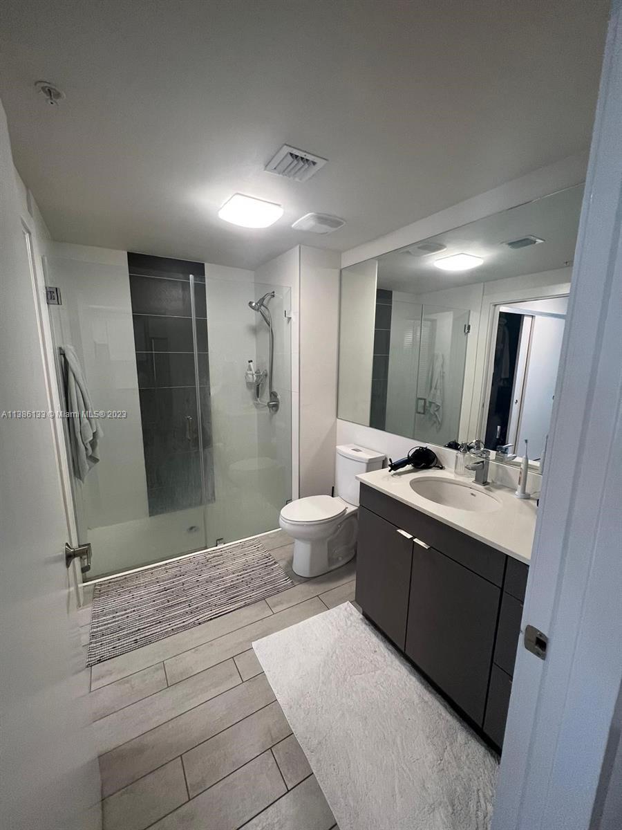 321 Northeast 26th Street, Unit 615 Miami, FL 33137 - Photo 10 of 15 a large bathroom with a double vanity sink toilet mirror and shower