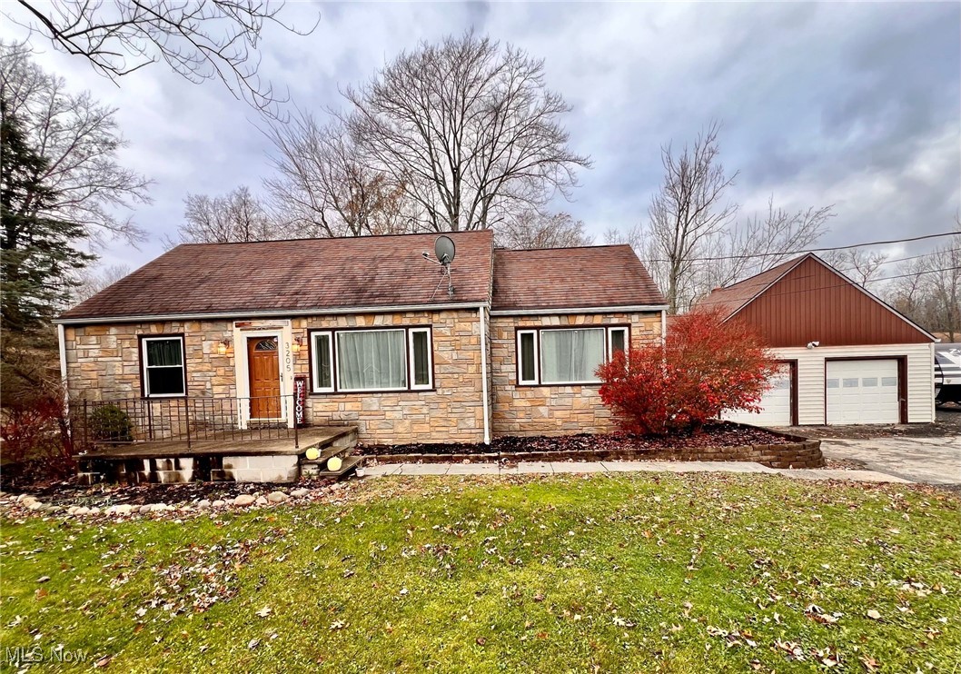 View of front of house featuring an outbuilding, a garage, and a front lawn