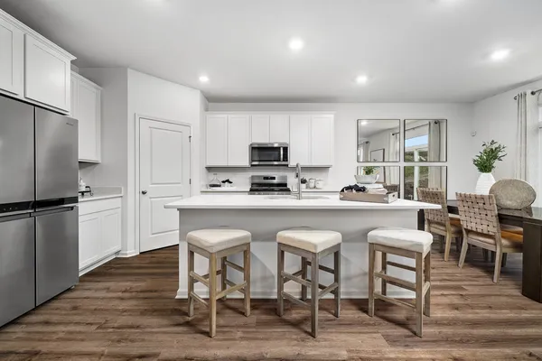 a kitchen with stainless steel appliances a table chairs refrigerator and microwave
