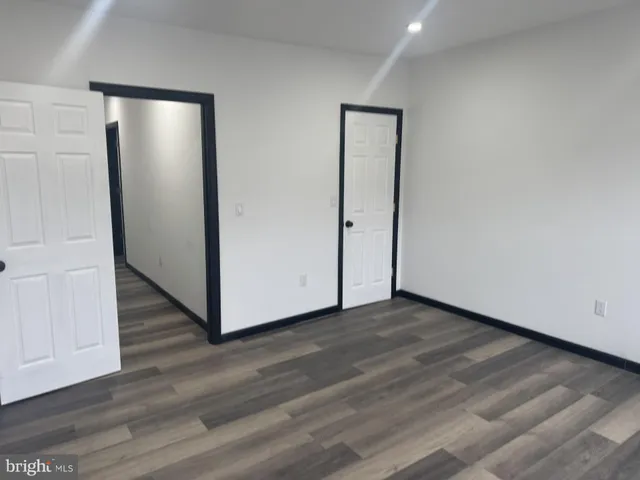 a view of an empty room with wooden floor and a bathroom