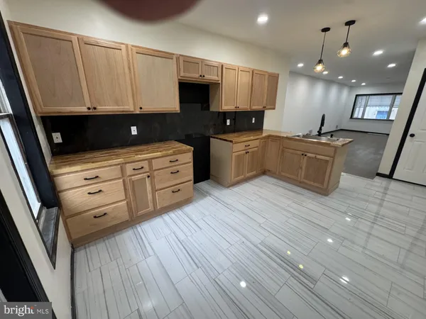 a large kitchen with stainless steel appliances a large counter top a stove a sink and a refrigerator