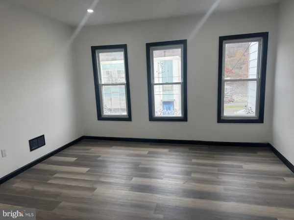 an empty room with wooden floor and windows