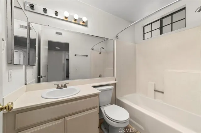 a bathroom with a sink a toilet a mirror a vanity and bathtub