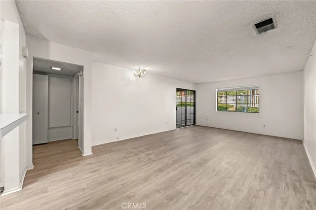 a view of an empty room with a window and wooden floor