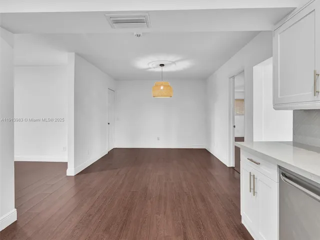 a open kitchen with granite countertop a stove a sink and white cabinets with wooden floor next to windows
