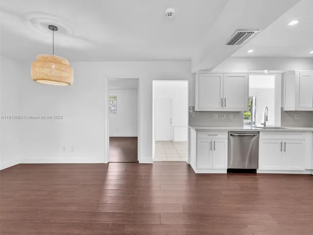 a kitchen with white cabinets white stainless steel appliances and wooden floors