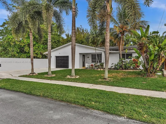 a view of a house with a yard and palm trees