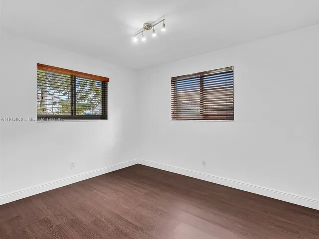an empty room with wooden floor ceiling fan and windows
