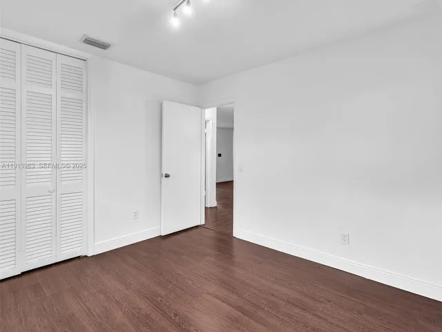 an empty room with wooden floor ceiling fan and windows