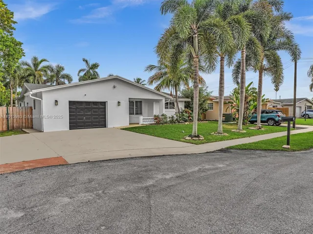 a view of a white house with a yard and palm trees