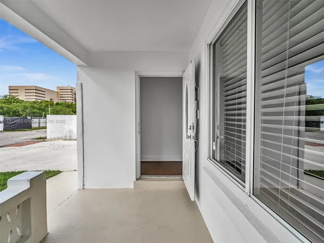 a view of empty room with wooden floor and kitchen