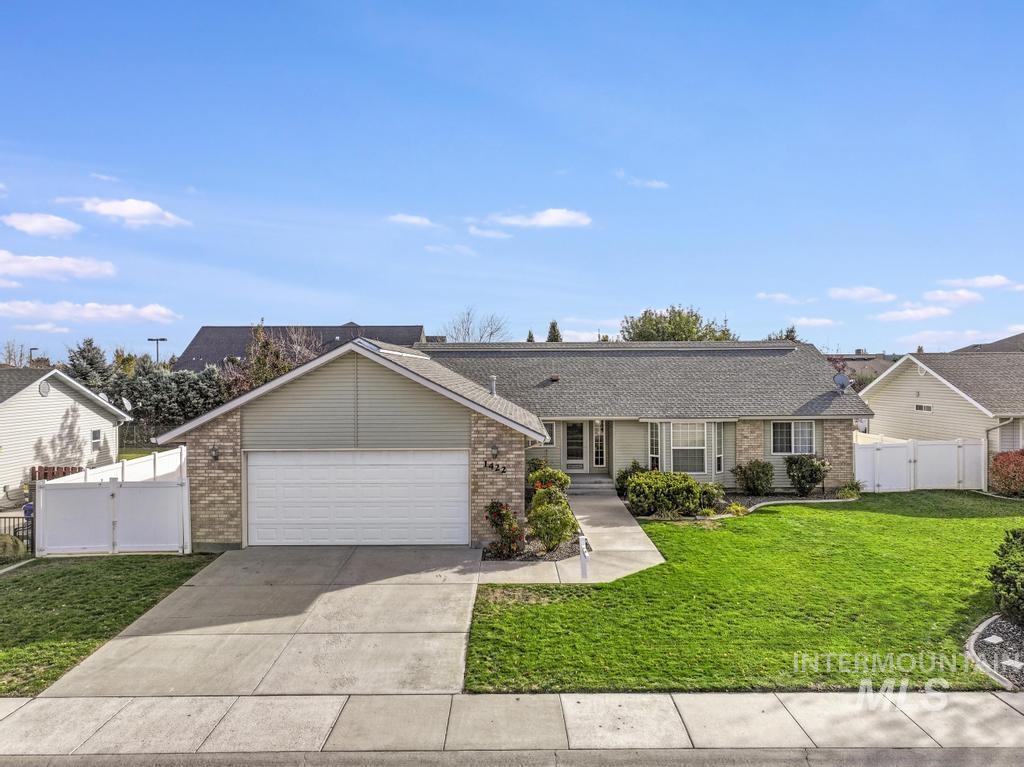 View of front of property with driveway, brick siding, an attached garage, and a gate