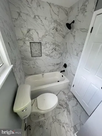 a white toilet sitting next to a bath tub