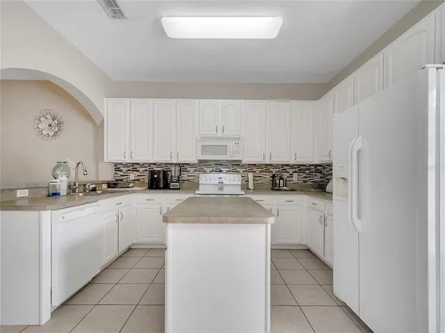 a kitchen with granite countertop white cabinets and white appliances