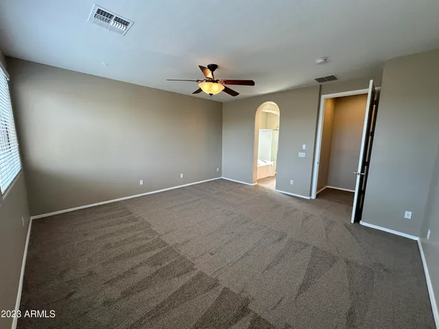 an empty room with windows and chandelier fan