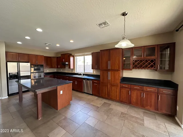 a kitchen with stainless steel appliances granite countertop wooden cabinets a sink and a refrigerator