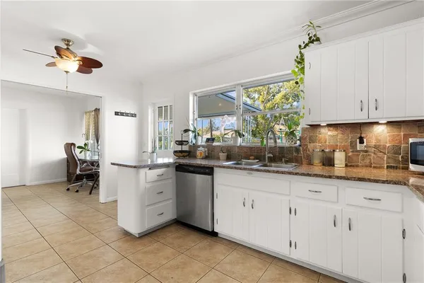 a kitchen with white cabinets and sink