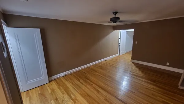 an empty room with wooden floor cabinet and a ceiling fan