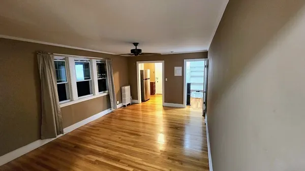 a view of an empty room with wooden floor and a window