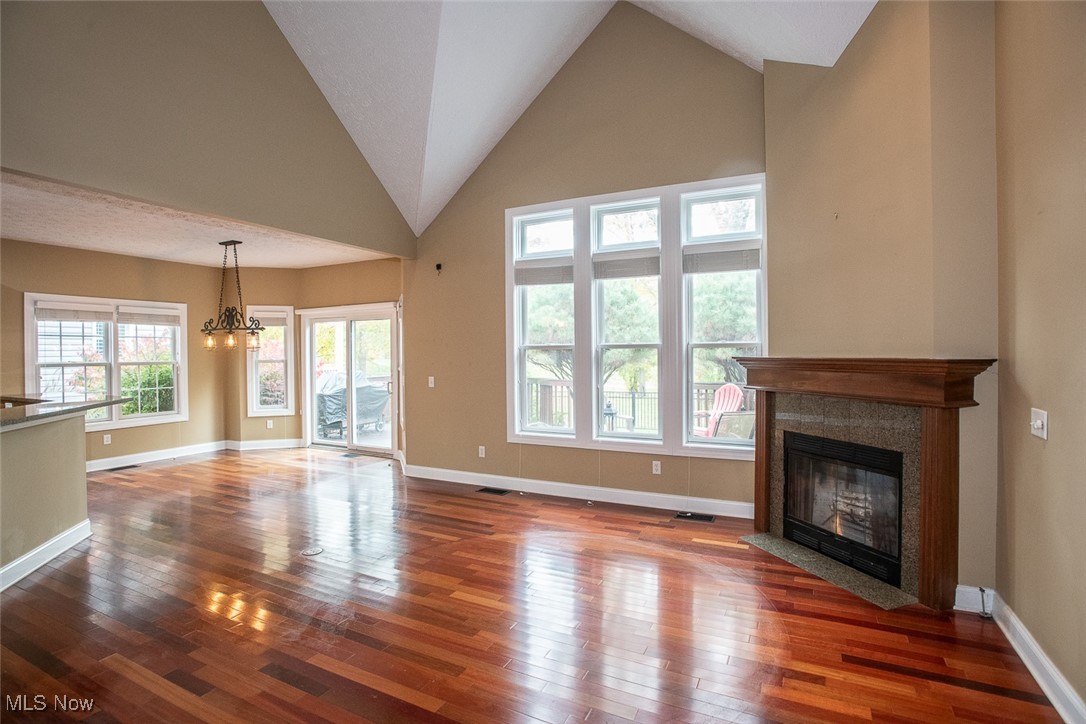 630 Rundle Street Lagrange, OH 44050 - Photo 10 of 49 Unfurnished living room with high vaulted ceiling, a fireplace with flush hearth, hardwood / wood-style floors, and a chandelier