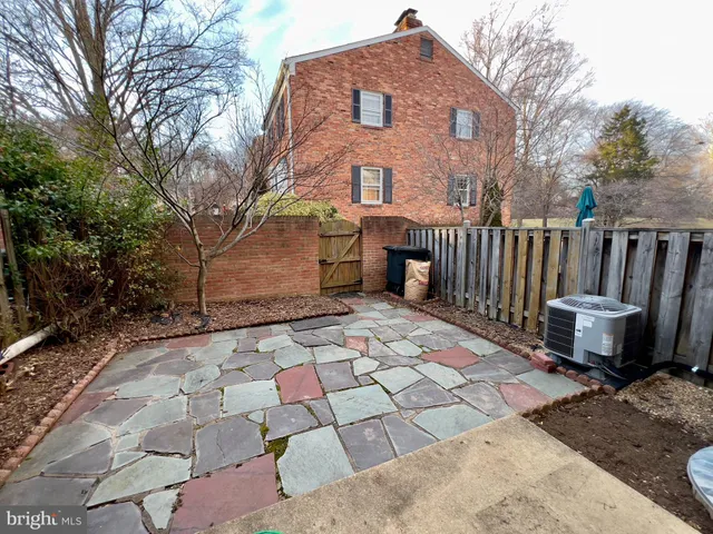 a brick house with wooden fence next to a yard